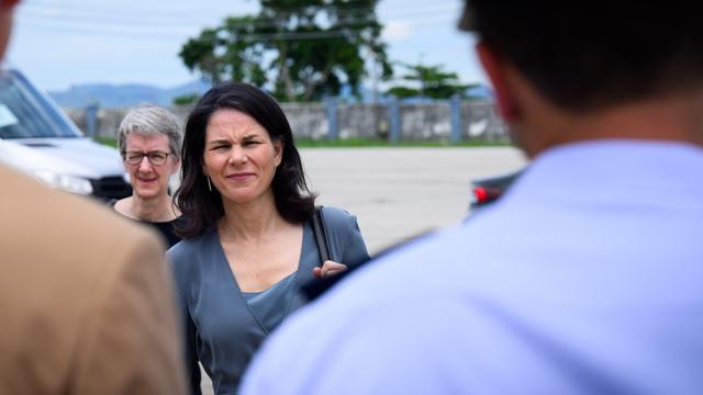 Eine Frau mit zusammen gekniffenen Augen blickt in die Kamera. Vor ihr stehen andere Personen, die nicht zu erkennen sind. Die Frau ist die deutsche Außenministerin Annalena Baerbock.