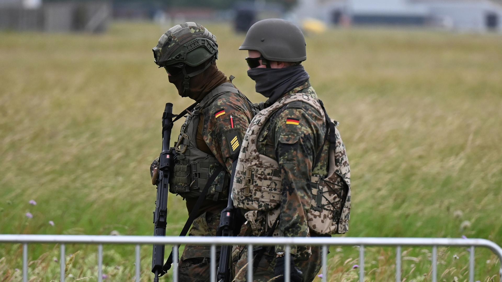 Soldaten der Bundeswehr gehen am Luftwaffenstützpunkt der Bundeswehr in Jagel durch hohes Gras.