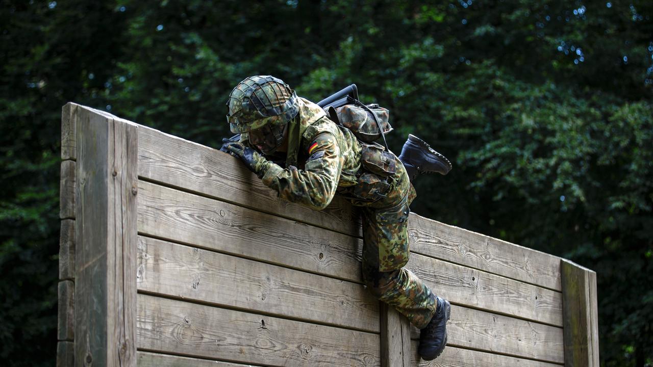 Ein Rekrut der Bundeswehr überwindet auf einem Hindernisparcours Holzlatten. 