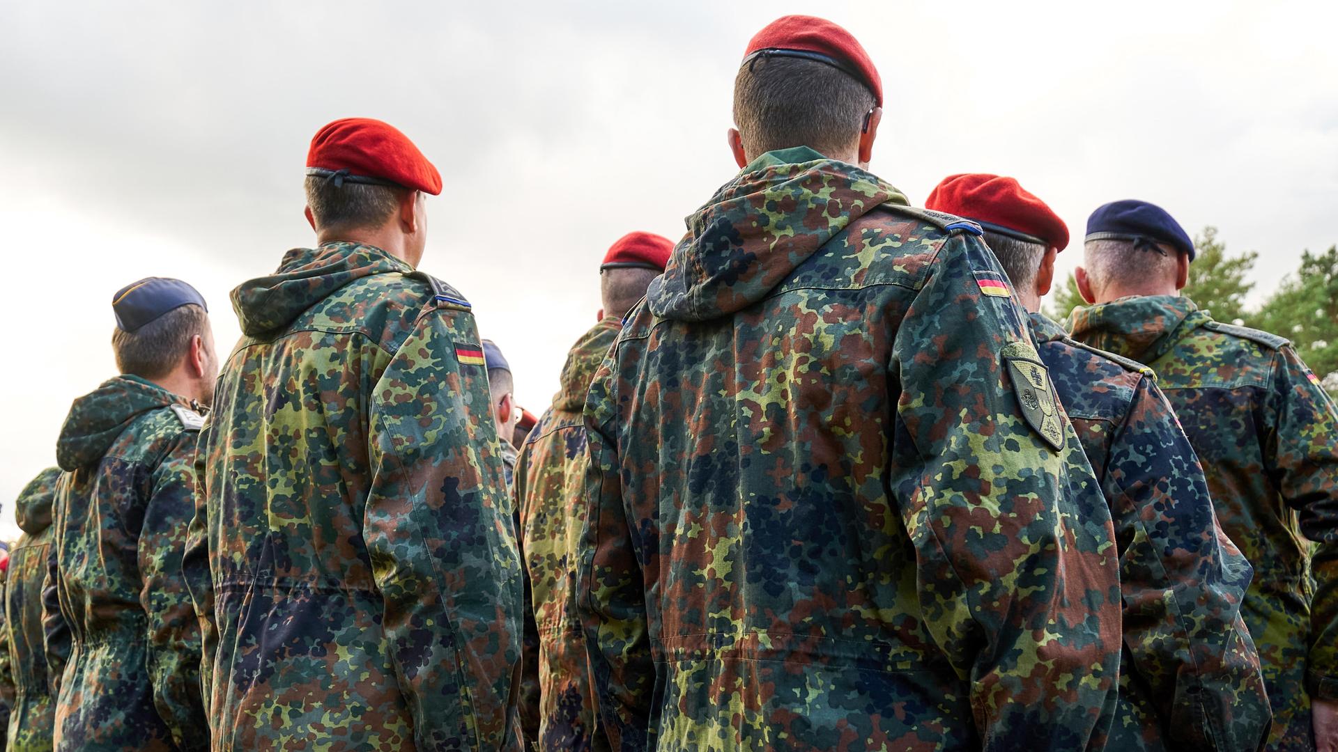 Soldaten der Bundeswehr stehen in Reih und Glied, gekleidet in Flecktarnuniformen und tragen rote Baretts Soldaten der Bundeswehr stehen in Reih und Glied, gekleidet in Flecktarnuniformen und tragen rote Baretts