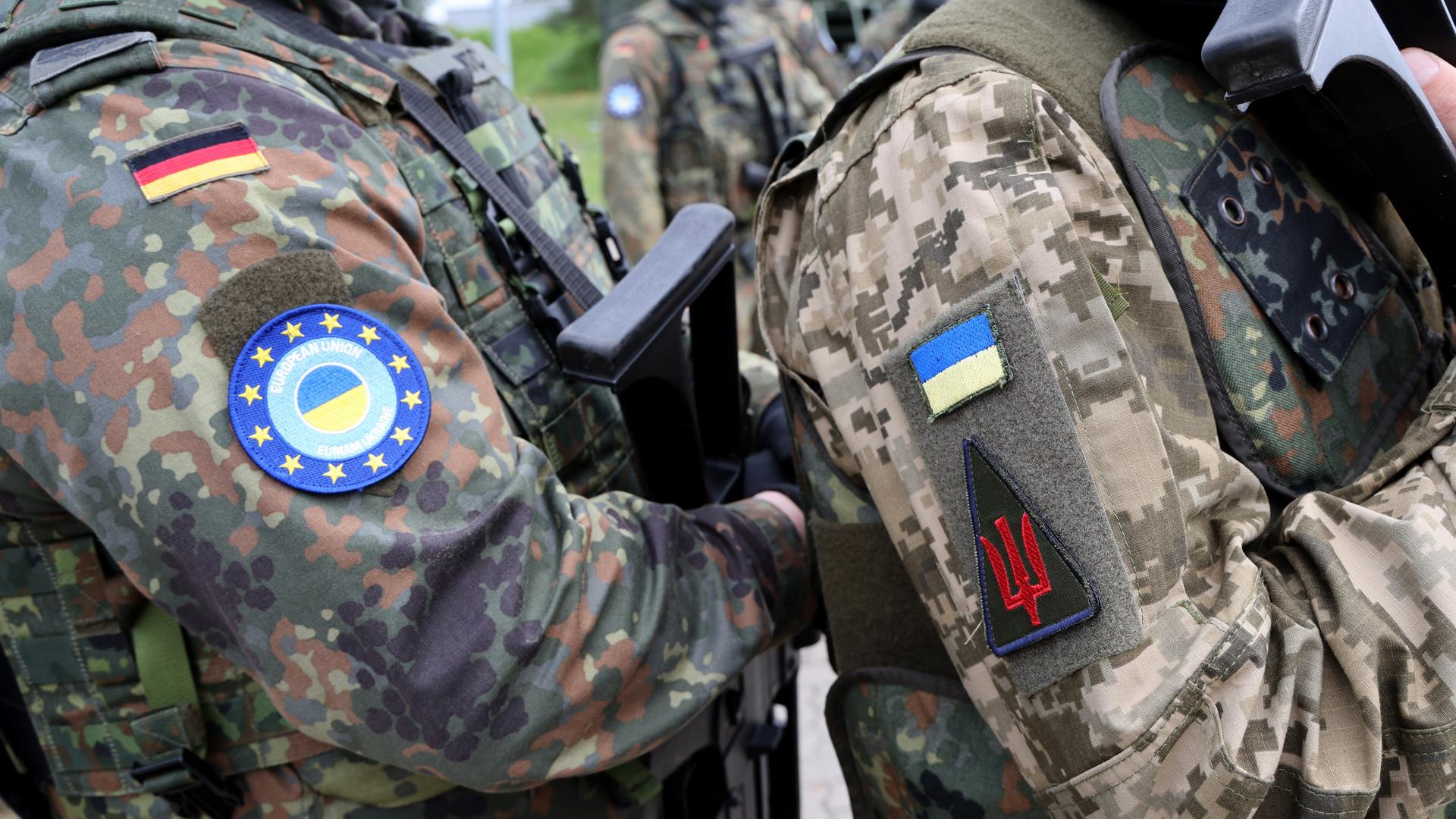 Schulter an Schulter stehen ein deutscher und ein ukrainischer Soldat auf einem Truppenübungsplatz. Man sieht nur die Uniform. Schulter an Schulter stehen ein deutscher und ein ukrainischer Soldat auf einem Truppenübungsplatz. Man sieht nur die Uniform.