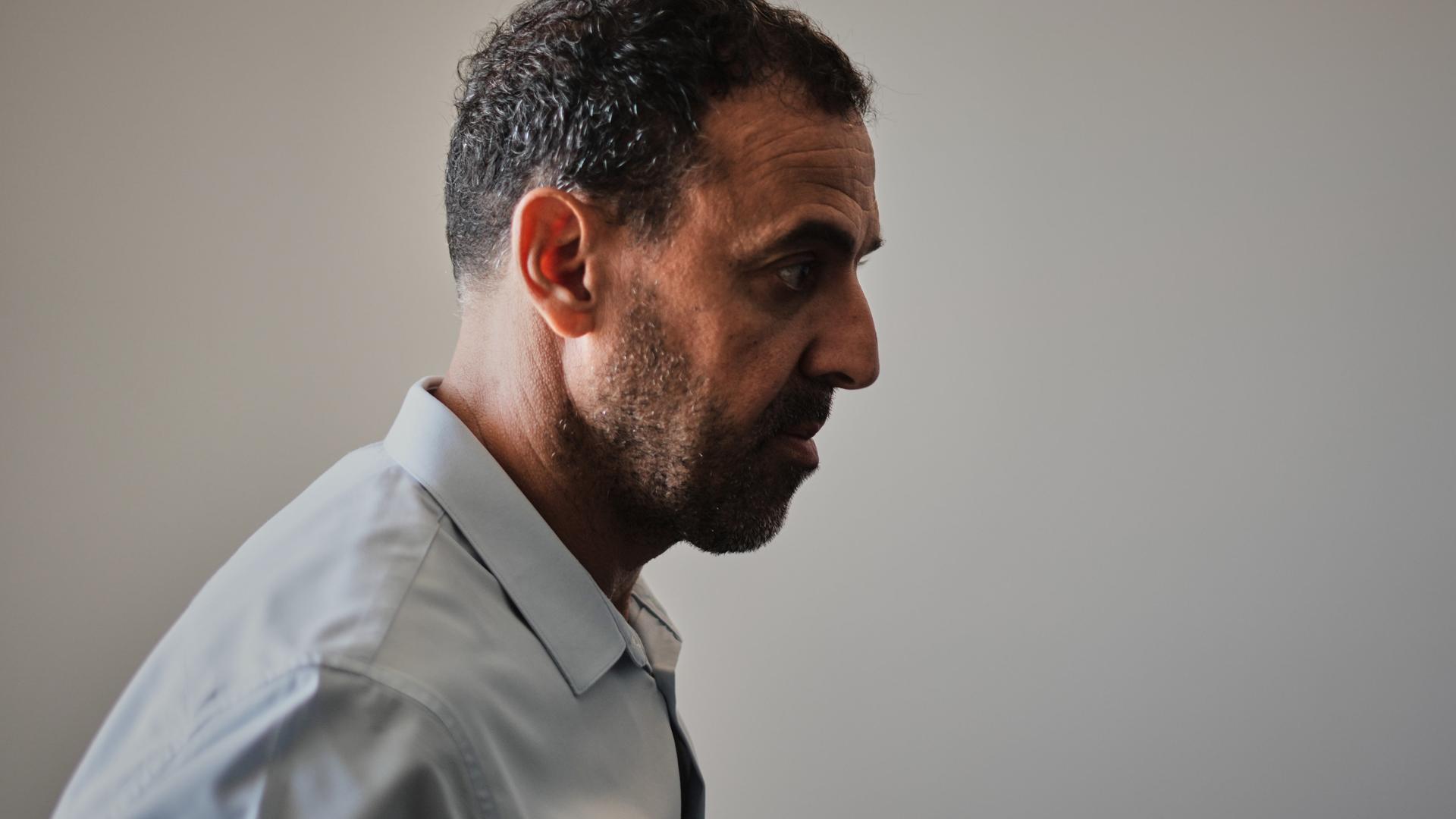 Ein Mann in Anzug, im Profil. Er blickt ernst: der Israeli Eli Sharabi, ehemals Geisel der Hamas.
