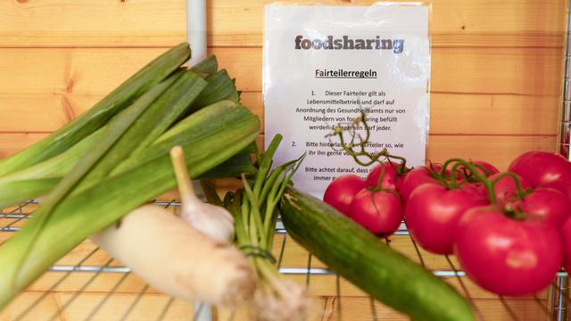 Lauch, eine Gurke und Tomaten liegen in einem Fach, dahinter hängt ein Zettel, auf dem "foodsharing" steht. Lauch, eine Gurke und Tomaten liegen in einem Fach, dahinter hängt ein Zettel, auf dem "foodsharing" steht.