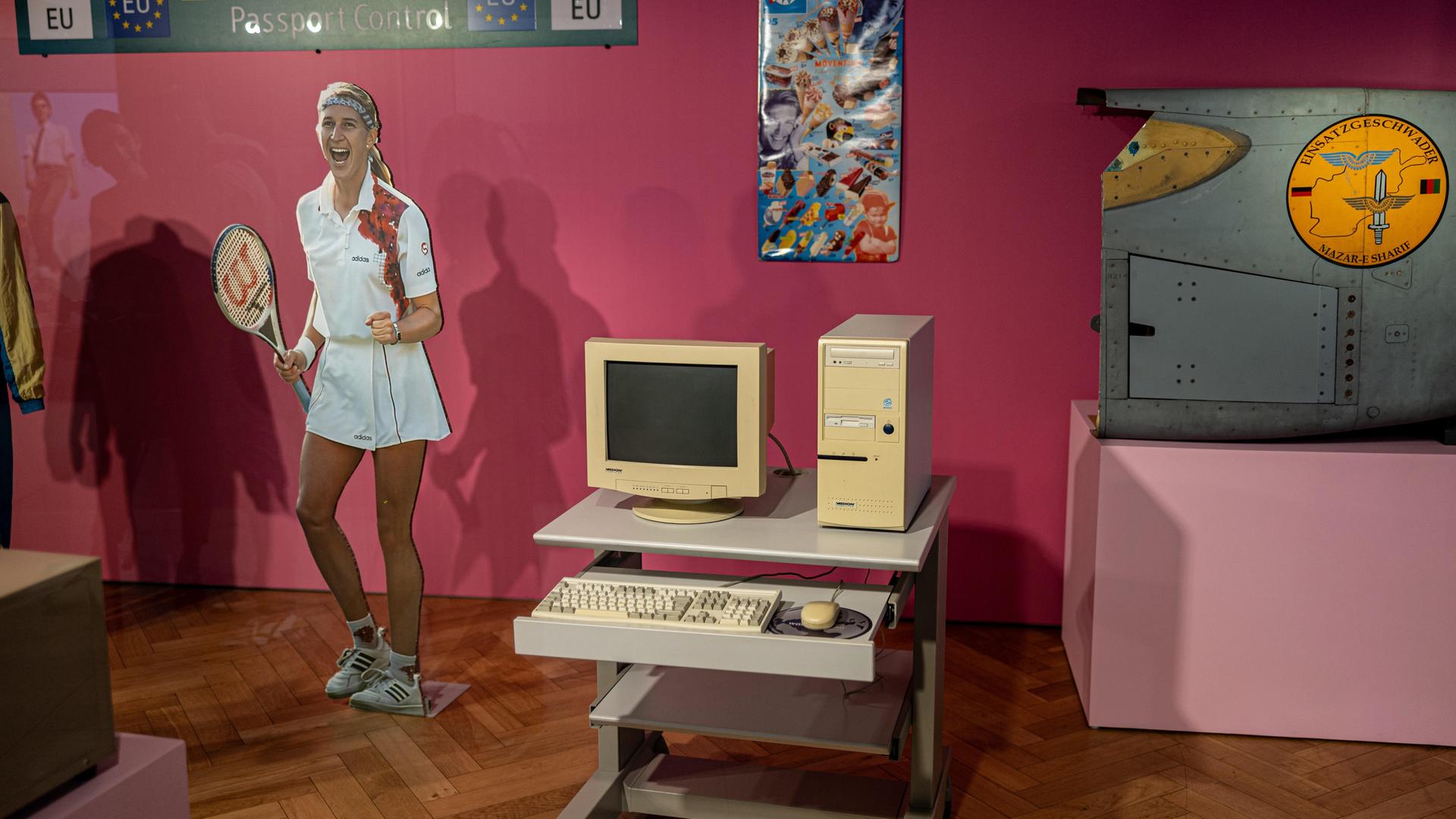 Das Bild zeigt einen Raum der neuen Dauerausstellung im Haus der Geschichte in Bonn, u.a. einen ALDI PC von 1997, einen Pappaufsteller von Steffi Graf und ein Verkaufsschild von Eiscreme