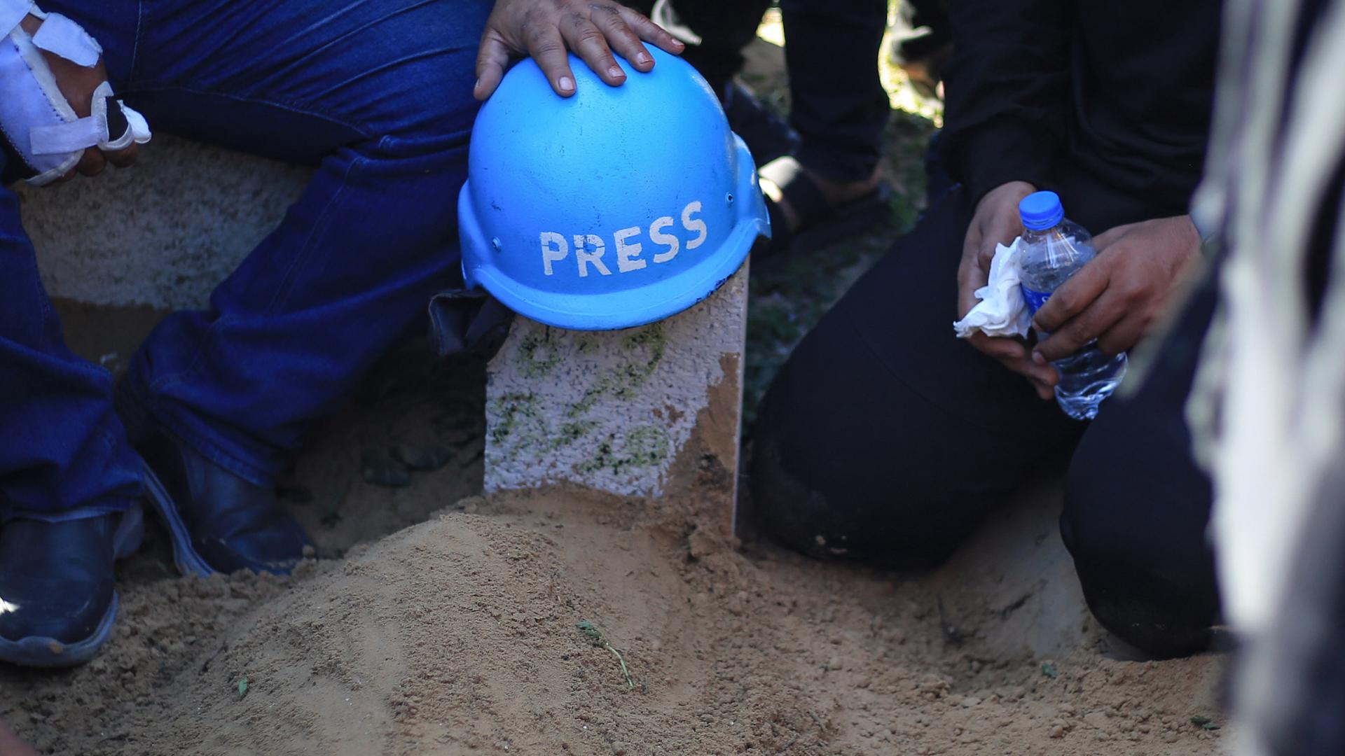 Blauer Stahlhelm mit Aufschrift "Press" auf einem Grab in Gaza.