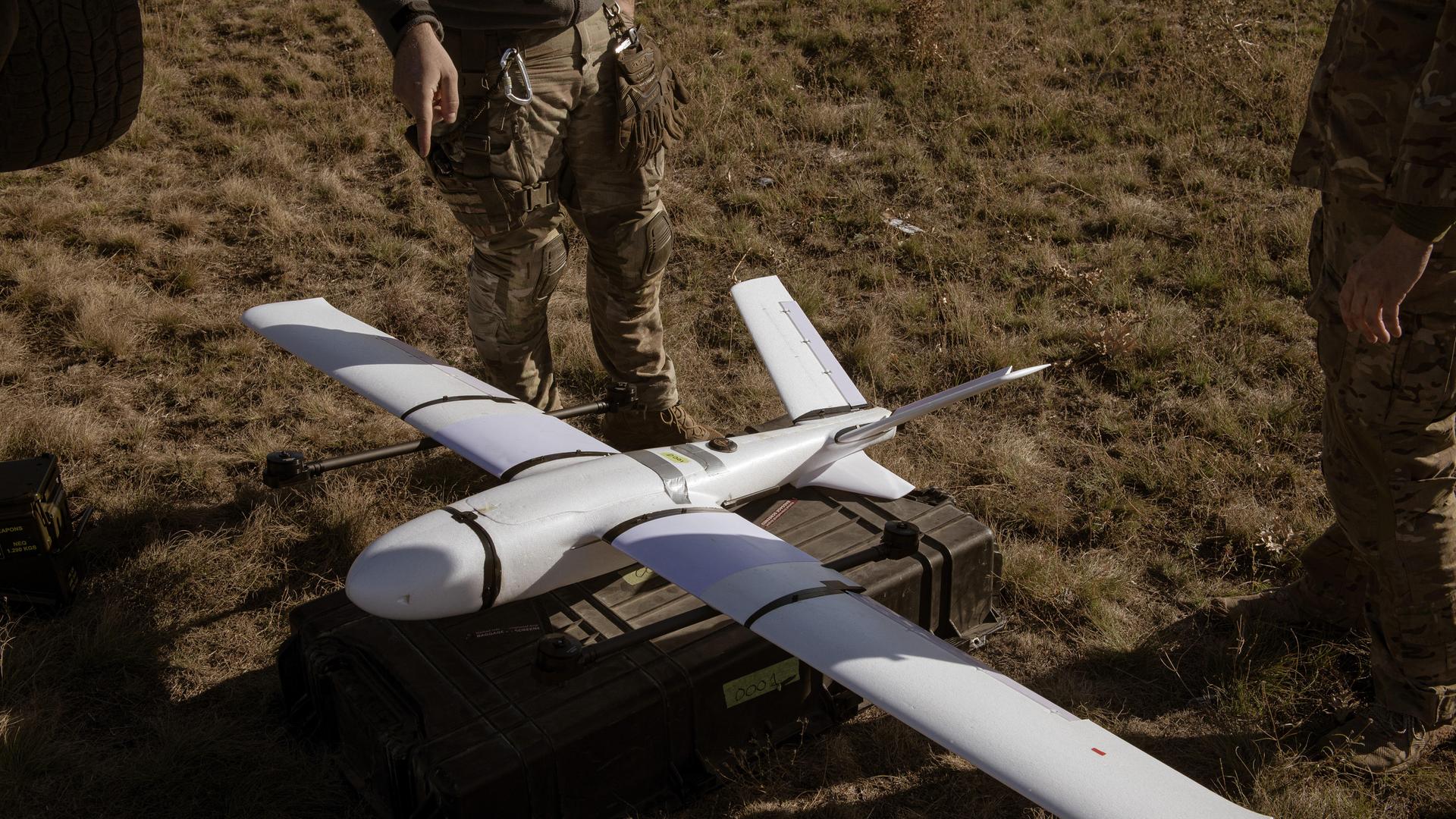 Zwei Soldaten stehen neben dem Protoypen einer Drohne, die auf dem Boden zum Einsatz bereit liegt. Zwei Soldaten stehen neben dem Protoypen einer Drohne, die auf dem Boden zum Einsatz bereit liegt.