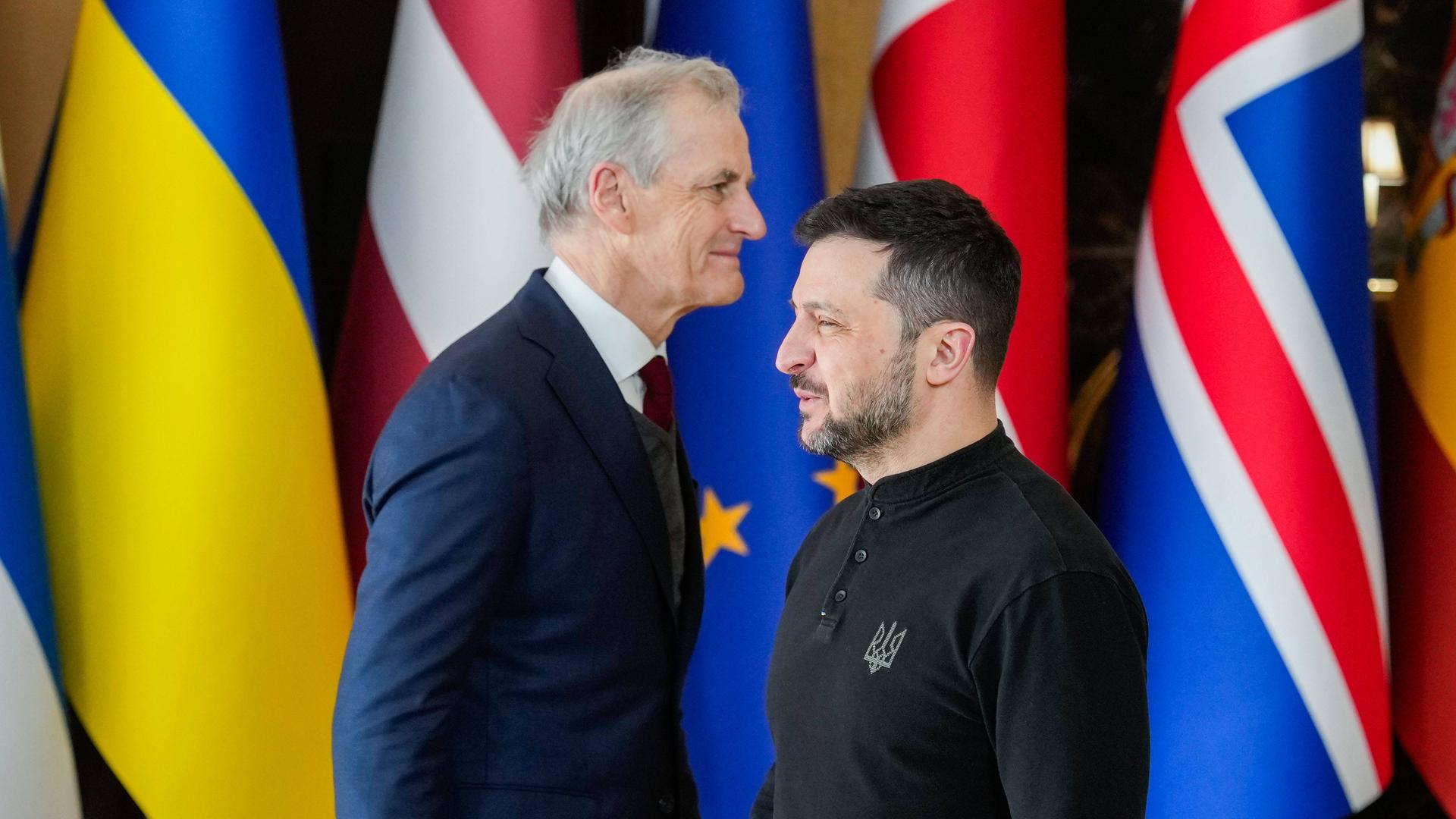Der norwegische Premierminister Jonas Gahr Stoere und der ukrainische Präsident Volodymyr Selenskyj. Vor verschiedenen Flaggen gehen sie aneinander vorbei. Der norwegische Premierminister Jonas Gahr Stoere und der ukrainische Präsident Volodymyr Selenskyj. Vor verschiedenen Flaggen gehen sie aneinander vorbei.