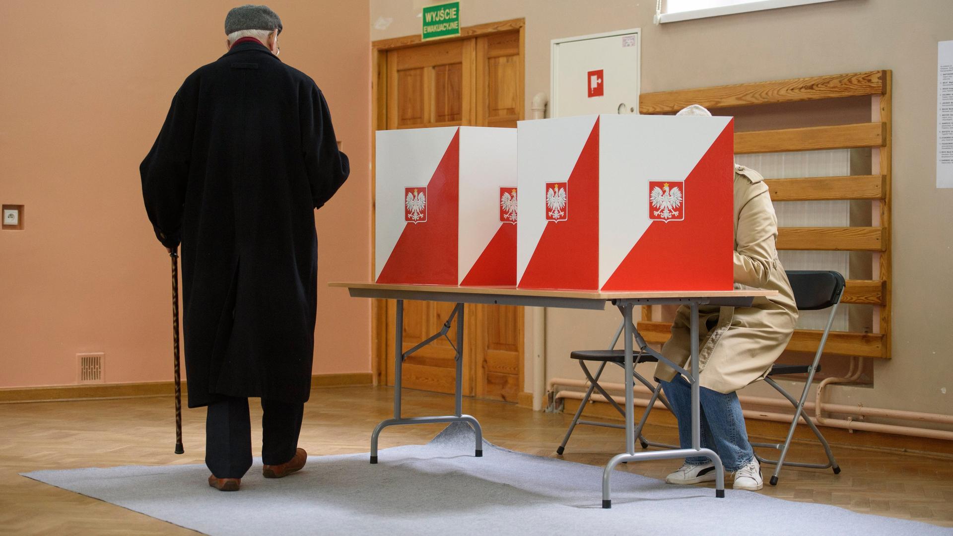 Ein Mann im schwarzen Mantel von hinten im Wahllokal in Warschau. Ein Mann im schwarzen Mantel von hinten im Wahllokal in Warschau.