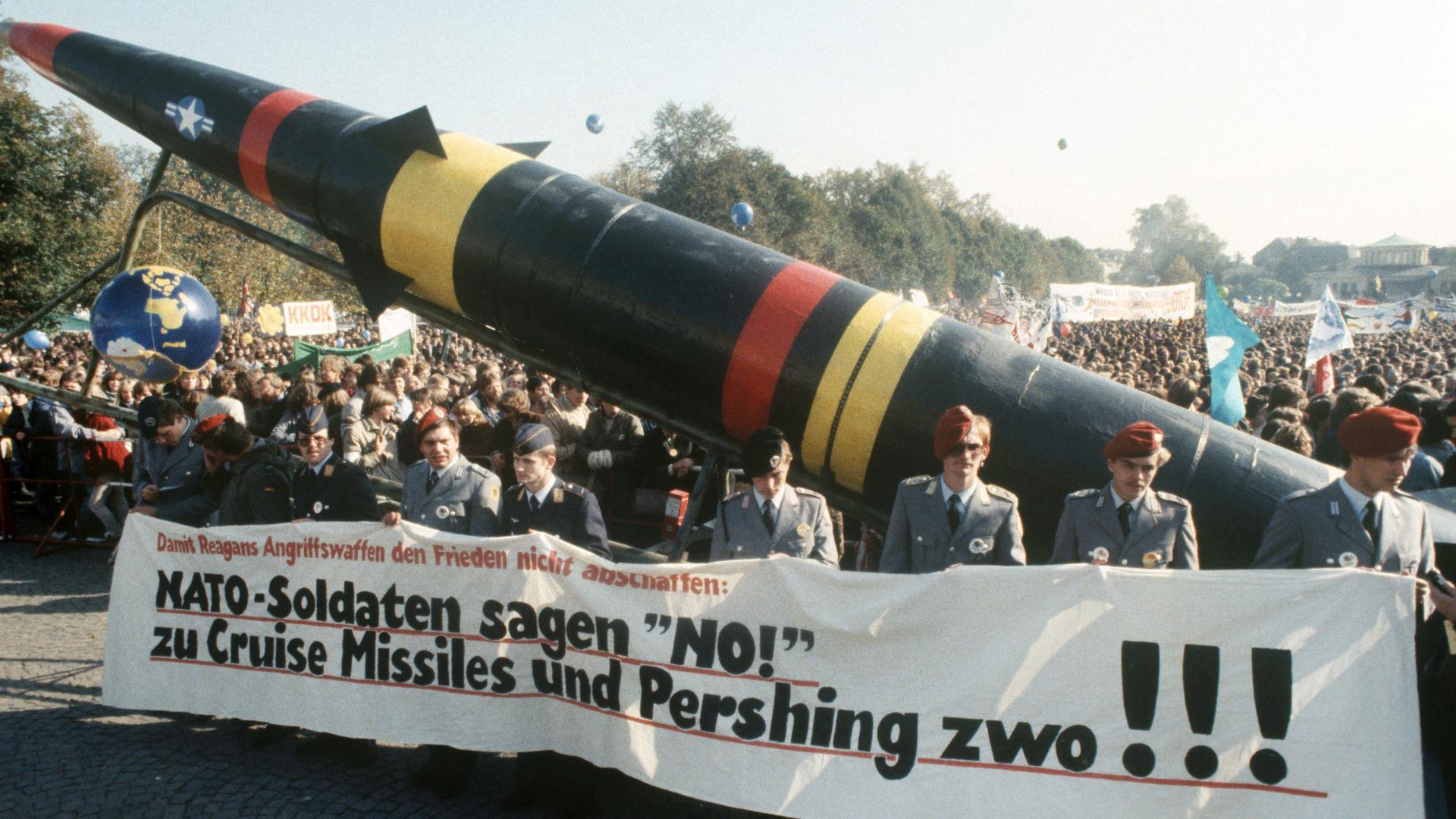 Soldaten der Bundeswehr in Uniform laufen mit einem Transparent und einer Pershing-II-Attrappe bei einer Demonstration gegen die NATO-Hochrüstung. Soldaten der Bundeswehr in Uniform laufen mit einem Transparent und einer Pershing-II-Attrappe bei einer Demonstration gegen die NATO-Hochrüstung.