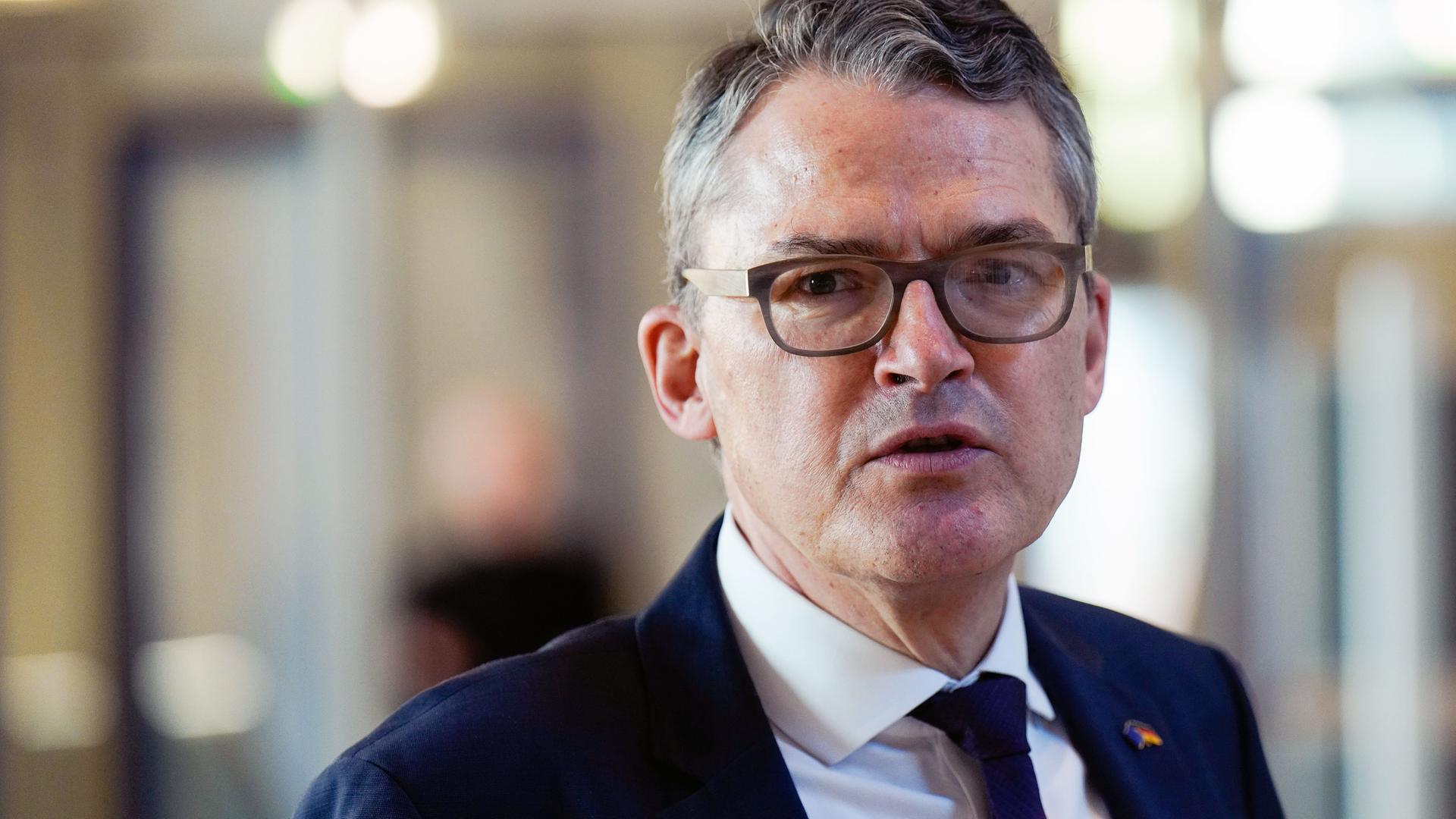 Roderich Kiesewetter trägt Anzug und blickt in die Kamera, im Hintergrund ist verschwommen ein Innenraum im Reichstagsgebäude zu sehen Roderich Kiesewetter trägt Anzug und blickt in die Kamera, im Hintergrund ist verschwommen ein Innenraum im Reichstagsgebäude zu sehen