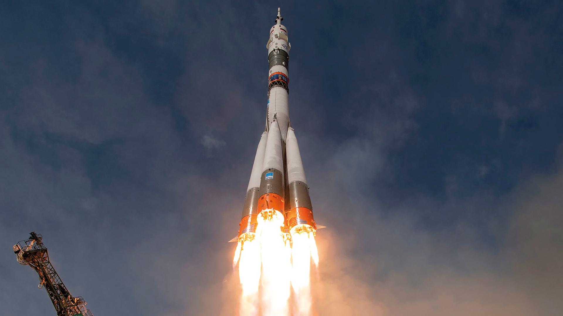 Eine Soyuz-Rakete startet vom Weltraumbahnhof in Baikonur. Aus den gezündeten Triebwerken kommt Feuer.