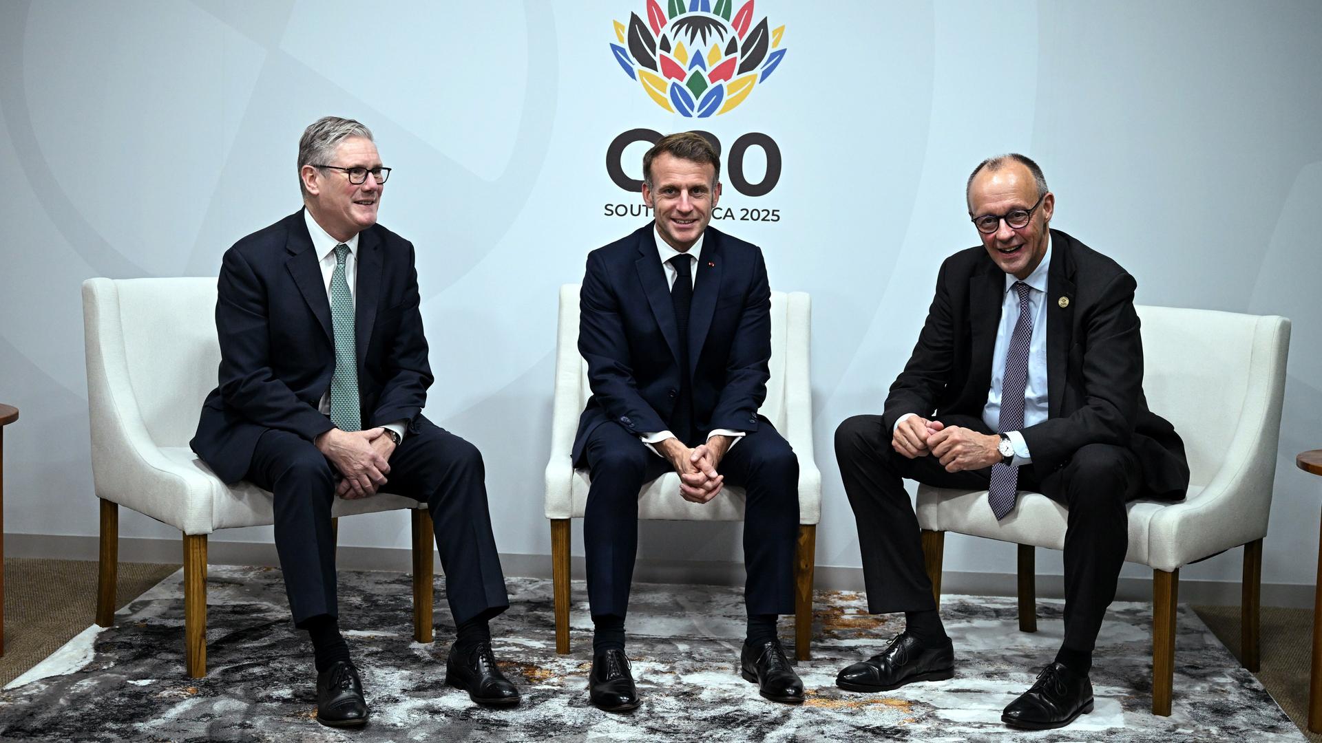 Der britische Premierminister Keir Starmer (links), Frankreichs Präsident Emmanuel Macron (Mitte) und Bundeskanzler Friedrich Merz lächeln für die Kameras beim G20-Gipfel in Johannesburg Der britische Premierminister Keir Starmer (links), Frankreichs Präsident Emmanuel Macron (Mitte) und Bundeskanzler Friedrich Merz lächeln für die Kameras beim G20-Gipfel in Johannesburg