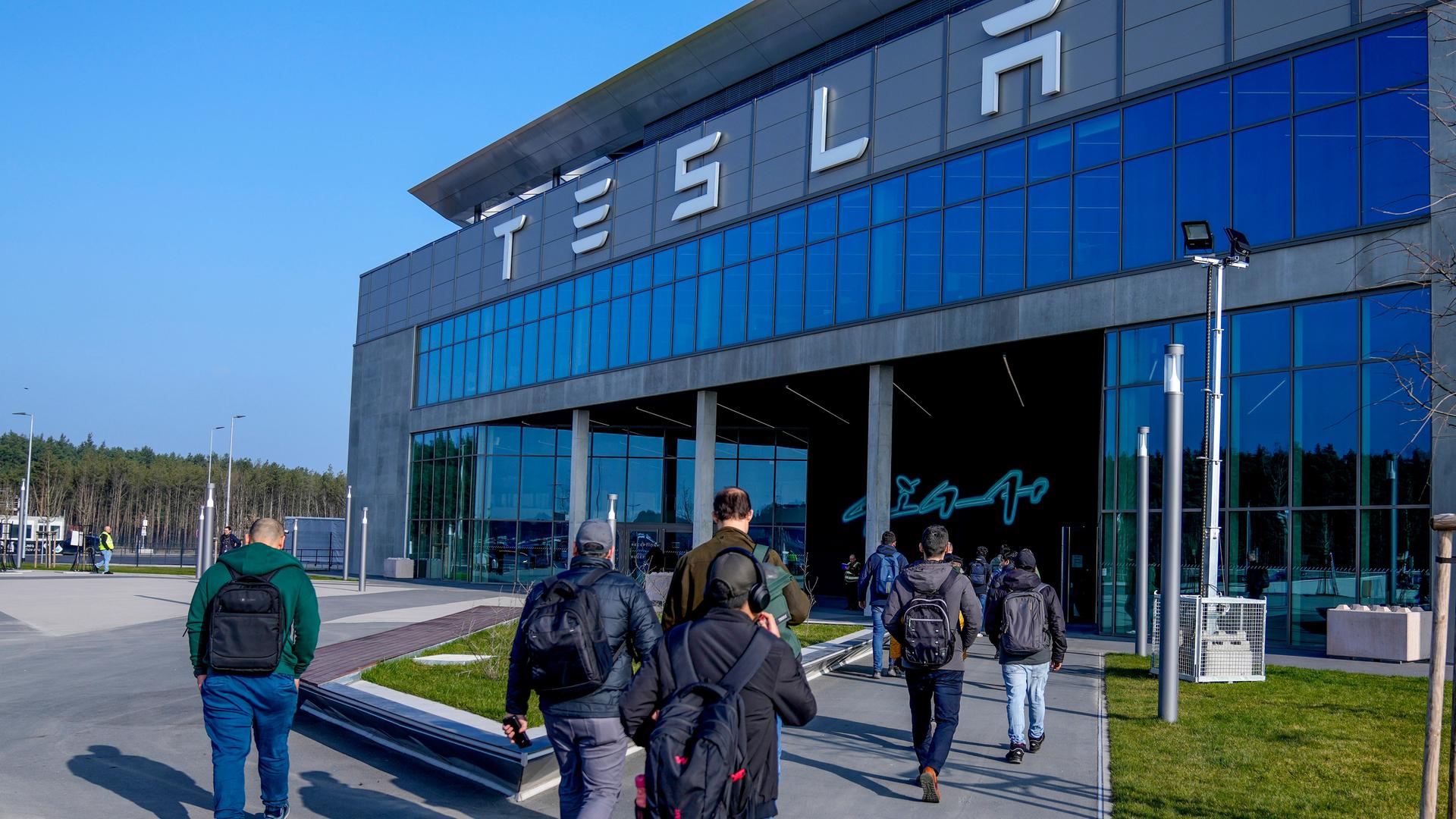 Menschen laufen in das Gebäude der Tesla-Fabrik in Grünheide in Brandenburg, nachdem die Produktion nach einem Brandanschlag auf die Stromversorgung wieder angelaufen war. 

