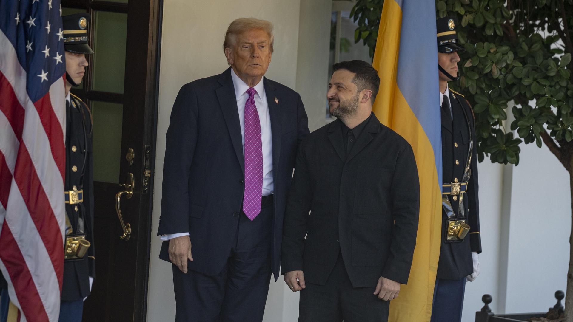 US-Präsident Donald Trump und der ukrainische Präsident Selenskyj stehen vor dem Weißen Haus. Selenskyi schaut zu Trump. Im Hintergrund sind US-Soldaten und die Landesfahne zu sehen. US-Präsident Donald Trump und der ukrainische Präsident Selenskyj stehen vor dem Weißen Haus. Selenskyi schaut zu Trump. Im Hintergrund sind US-Soldaten und die Landesfahne zu sehen.