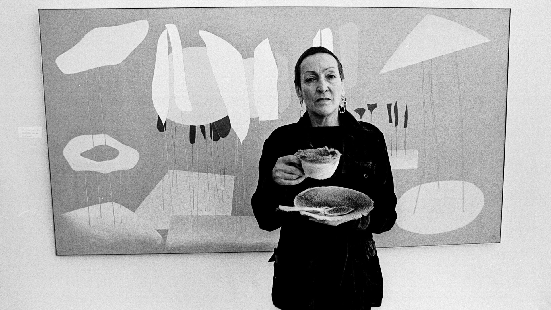 Meret Oppenheim hält in diesem Schwarz-weiß-Foto eine mit Pelz ausgekleidete Tasse bei der Eröffnung ihrer Ausstellung im Duisburger Wilhelm-Lehmbruck-Museum am 21.März 1975